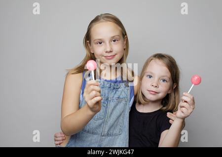 Entzückende junge Mädchen Kinder essen süße Lutscher Bonbons auf weißem Studio Wand Banner Hintergrund, Mode Porträt Stockfoto