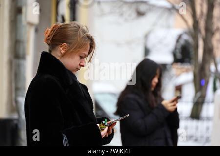 Frauen stehen mit Smartphones in der Hand auf der winterlichen Stadtstraße Stockfoto