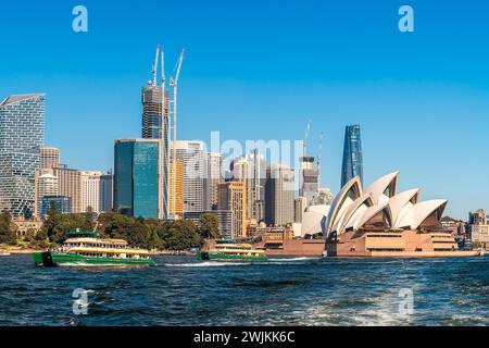 Sydney, Australien - 17. April 2022: Sydney Opera House und Fähren fahren an einem hellen, sonnigen Tag mit der modernen Skyline von Sydney City vorbei Stockfoto