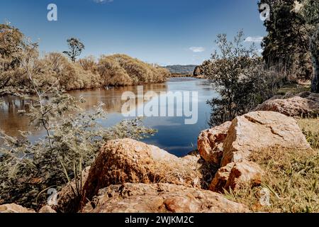 Ein ruhiger See, umgeben von üppigem Laub und felsigem Gelände Stockfoto