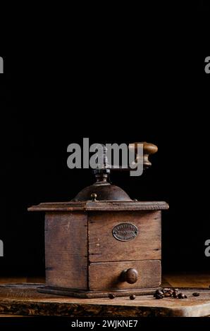Alte Kaffeemühle auf Holzoberfläche und dunklem Hintergrund Stockfoto