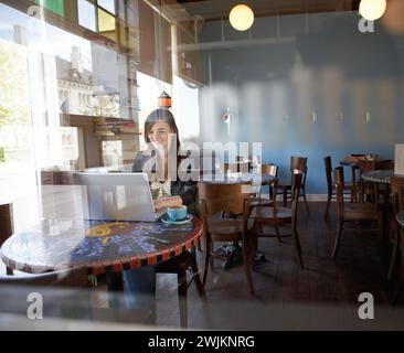 Frau, die in einem Café an einem Laptop arbeitet Stockfoto