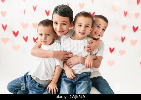 Fröhliche Kinder, die vor einem Hintergrund des Herzens lächeln und umarmen Stockfoto