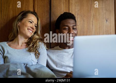 Glückliches Paar, das im Bett liegt und einen Laptop benutzt Stockfoto