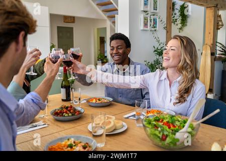 Gruppe von Freunden, die mit einer Weinbrille beim Abendessen im Speisesaal toasten Stockfoto
