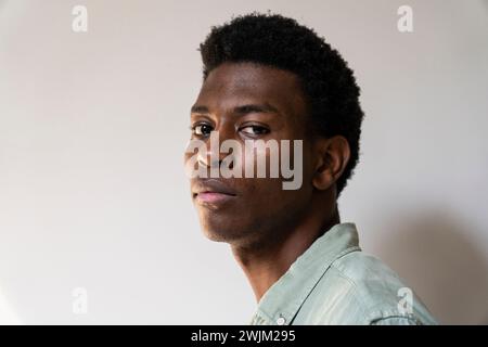 Seitenporträt eines jungen Erwachsenen, der in die Kamera blickt Stockfoto