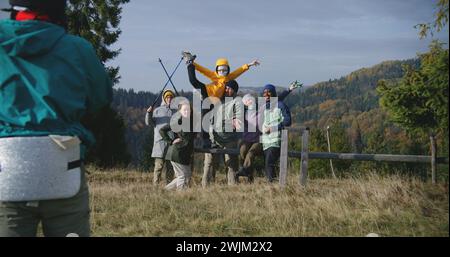 Ein Teenager-Wanderer macht Gruppenfotos von seinen multiethnischen Freunden oder Familie auf dem Gipfel des Hügels mit malerischer Aussicht auf die Natur. Vielfältige Touristen oder Reisende bei Wanderungen in den Bergen. Tourismus und Reisen. Stockfoto