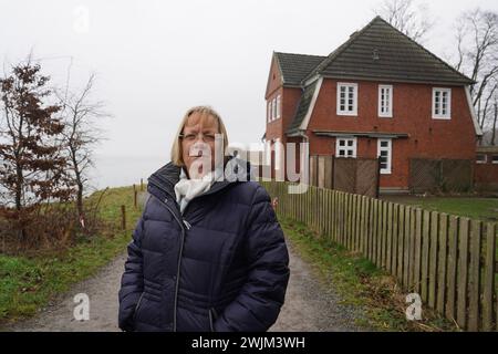 PRODUKTION - 14. Februar 2024, Schleswig-Holstein, Lübeck-Travemünde: Renate Paulien-Wittmaack, Bezirksvorsitzende der Jugendorganisation SJD - die Falken, steht vor dem Jugendzentrum "Haus Seeblick" im Brodten-Bezirk an der Ostsee. Das Jugendzentrum Haus Seeblick, direkt an den Brodtenfelsen gelegen, ist nach einem weiteren Randabbruch für Kinder- und Jugendarbeit geschlossen. Nur gut vier Meter liegen zwischen einer Ecke des 'Haus Seeblick' und dem Abgrund. Ende Januar fiel ein Baum entlang des Randes und hinterließ ein Loch im Fußweg vor dem Haus. Foto: Marc Stockfoto