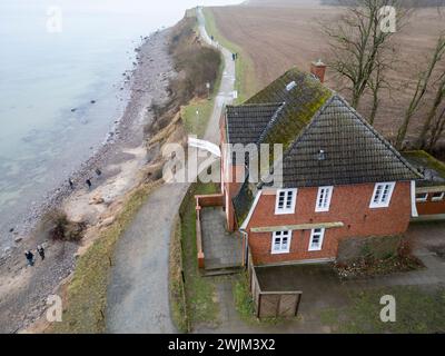 PRODUKTION - 14. Februar 2024, Schleswig-Holstein, Lübeck-Travemünde: Blick auf die Klippen und das Jugendzentrum Haus Seeblick der Jugendorganisation SJD - die Falken, auf die Klippen in Brodten an der Ostsee (Drohnenaufnahme). Das Jugendzentrum Haus Seeblick, direkt an den Brodtenfelsen gelegen, ist nach einem weiteren Randabbruch für Kinder- und Jugendarbeit geschlossen. Nur gut vier Meter liegen zwischen einer Ecke des 'Haus Seeblick' und dem Abgrund. Ende Januar fiel ein Baum entlang des Randes und hinterließ ein Loch im Fußweg vor dem Haus. Foto: Marcus Brandt/dpa Stockfoto