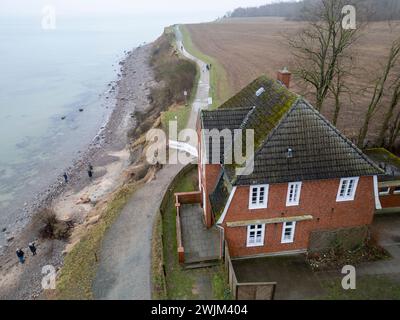 PRODUKTION - 14. Februar 2024, Schleswig-Holstein, Lübeck-Travemünde: Blick auf die Klippen und das Jugendzentrum Haus Seeblick der Jugendorganisation SJD - die Falken, auf die Klippen in Brodten an der Ostsee (Drohnenaufnahme). Das Jugendzentrum Haus Seeblick, direkt an den Brodtenfelsen gelegen, ist nach einem weiteren Randabbruch für Kinder- und Jugendarbeit geschlossen. Nur gut vier Meter liegen zwischen einer Ecke des 'Haus Seeblick' und dem Abgrund. Ende Januar fiel ein Baum entlang des Randes und hinterließ ein Loch im Fußweg vor dem Haus. Foto: Marcus Brandt/dpa Stockfoto