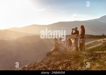 Eine große Gruppe junger Menschen entspannen sich in den Sonnenuntergangsbergen Stockfoto