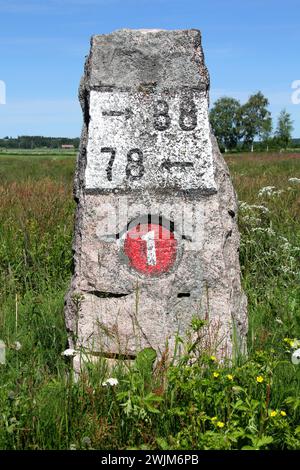 Alter Meilenstein aus Granit am Highway 110 (früher Nummer 1) in Kitula, Finnland mit Sommerlandschaft. Stockfoto