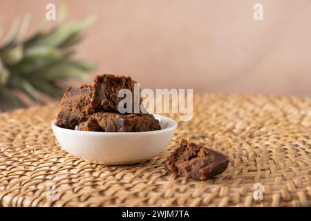 Kithul-Zierfräse und Treakle-natürliches Süßungsmittel in weißer Schüssel auf traditionellem Korbblech. Nahaufnahme. Vegane Nahrung mit niedrigem glykämischen Index. Superfood. Stockfoto