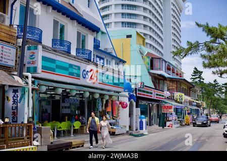 Gangneung City, Südkorea - 29. Juli 2019: Eine belebte Straße mit 24-Stunden-Geschäften und Restaurants liegt vor dem Gyeongpodae Beach, mit der majestätischen Skyba Stockfoto