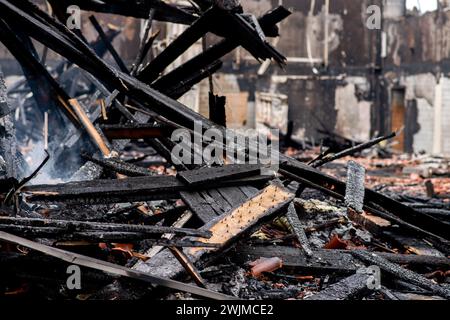 Neermoor, Deutschland. Februar 2024. Verkohlte Holzbalken der Dachkonstruktion liegen in der abgebrannten Sporthalle der Grundschule in Neermoor. Ein Brand zerstörte gestern Abend das Gymnasium in der Neermoor-Grundschule. Starke Winde und leicht brennbare Baumaterialien in der Halle führten dazu, dass sich das Feuer in eine größere Flamme mit fliegenden Funken und starkem Rauch ausbreitete. Quelle: Hauke-Christian Dittrich/dpa/Alamy Live News Stockfoto