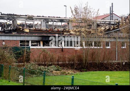 Neermoor, Deutschland. Februar 2024. Verbrannte Baumaterialien hängen vom Dach der abgebrannten Grundschulhalle in Neermoor. Ein Brand zerstörte gestern Abend das Gymnasium in der Neermoor-Grundschule. Starke Winde und leicht brennbare Baumaterialien in der Halle führten dazu, dass sich das Feuer in eine größere Flamme mit fliegenden Funken und starkem Rauch ausbreitete. Quelle: Hauke-Christian Dittrich/dpa/Alamy Live News Stockfoto