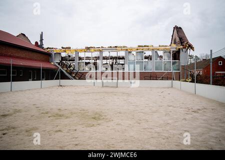 Neermoor, Deutschland. Februar 2024. Baumaterialien hängen vom Dach der abgebrannten Grundschulhalle in Neermoor. Ein Brand zerstörte gestern Abend das Gymnasium in der Neermoor-Grundschule. Starke Winde und leicht brennbare Baumaterialien in der Halle führten dazu, dass sich das Feuer in eine größere Flamme mit fliegenden Funken und starkem Rauch ausbreitete. Quelle: Hauke-Christian Dittrich/dpa/Alamy Live News Stockfoto