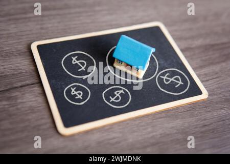 Nahaufnahme des Spielzeughauses und der Tafel. Immobilienblase, Immobilienblase Konzept. Stockfoto