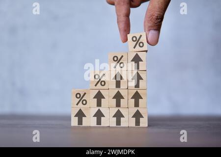 Zinssatz, Wachstum und Geschäftskonzept. Von Hand mit Holzwürfelblock mit dem Symbol Prozentwert oben auf dem Pfeil nach oben. Stockfoto