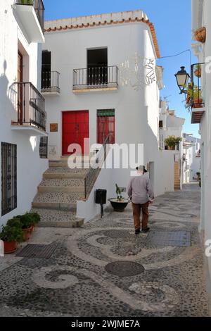 FRIGILIANA, ANDALUSIEN, SPANIEN - 24. DEZEMBER 2023: Eine malerische Kopfsteinpflasterallee mit traditionellen weiß getünchten kleinen Häusern Stockfoto