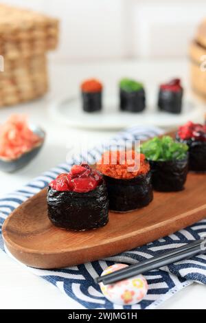 Hausgemachte Sushi Gunkan Maki mit verschiedenen Belägen auf Holzplatte Stockfoto