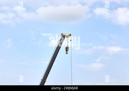 Detail von einem fliegenden Frachtkran über blauem Himmel Hintergrund. Auslegerkran Teil eines mobilen Krans, der in vielen Branchen zum schweren Heben und Bewegen von Objekten verwendet wird Stockfoto