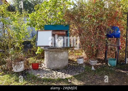 Alte Ziehbrunnen im europäischen Dorf. Retro Steinwasserbrunnen in ländlicher Umgebung Stockfoto