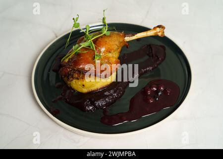 Gebratene Entenkeule auf Kartoffelpüree mit Zwiebeln, Purpurkohl-Creme und Heidelbeerjus Stockfoto