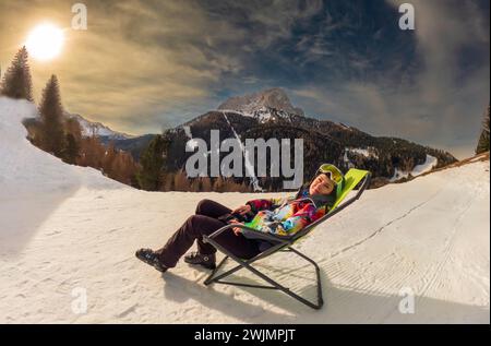 Junge Frau, die sich nach dem Skifahren auf einem Sessel entspannt, Dolomiten, Italien, Selaronda, Italien Stockfoto