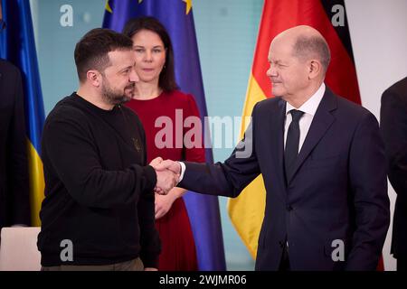 Berlin, Deutschland. Februar 2024. Der ukrainische Präsident Wolodymyr Zelenskyj links und der deutsche Bundeskanzler Olaf Schotz rechts schütteln sich nach einer Unterzeichnungszeremonie die Hand, als die deutsche Außenministerin Annalena Baerbock, Mitte, dem Bundeskanzleramt am 16. Februar 2024 in Berlin, Ukraine, die Hand. Quelle: Pool Photo/Ukrainische Präsidentenpresse/Alamy Live News Stockfoto