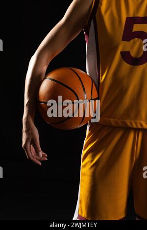 Basketballspieler in Aktion auf dunklem Hintergrund mit schwarzem Hintergrund Stockfoto