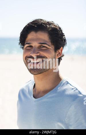 Junger Mann aus der Rasse lächelt hell draußen am Strand Stockfoto