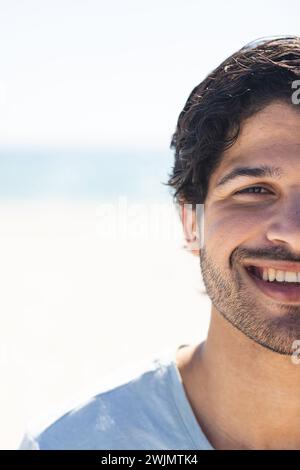 Junger birassischer Mann lächelt hell draußen am Strand, mit Kopierraum Stockfoto