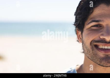 Ein junger birassischer Mann lächelt hell am Strand, mit Kopierraum Stockfoto
