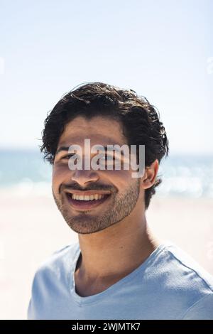 Ein junger, birassischer Mann lächelt hell am Strand Stockfoto