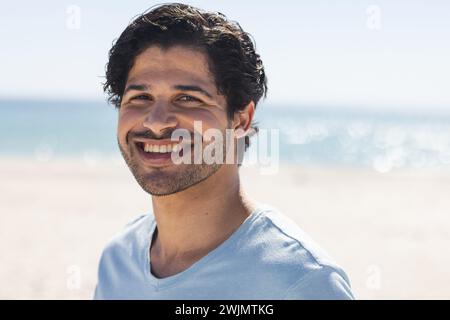Junger Mann aus der Rasse lächelt hell draußen am Strand Stockfoto