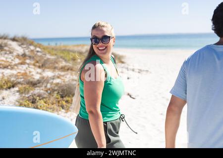 Verschiedene Freunde, darunter eine junge kaukasische Frau und ein Mann der Rasse, genießen einen sonnigen Strandtag Stockfoto