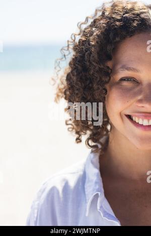 Eine junge Frau mit birassischer Rasse lächelt hell am Strand Stockfoto