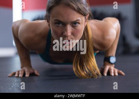 Eine gute junge weiße Frau, die Liegestütze im Fitnessstudio macht Stockfoto