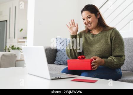 Eine junge Frau in Übergröße genießt eine virtuelle Feier zu Hause Stockfoto