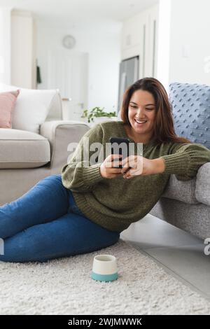 Eine junge Frau in Übergröße genießt ihr Smartphone zu Hause Stockfoto