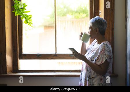 Eine reife, birassische Seniorin genießt einen Morgenkaffee zu Hause, mit unverändertem Kopierraum Stockfoto