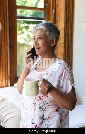 Eine reife birassische Frau genießt zu Hause ein Telefongespräch Stockfoto