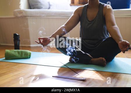 Eine reife, birassische Frau meditiert drinnen Stockfoto