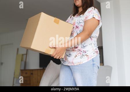 Junge birassische und große Frau, die zu Hause eine Pappschachtel hält Stockfoto