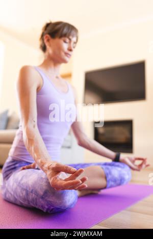 Kaukasische Frau mittleren Alters übt Yoga zu Hause, mit Kopierraum Stockfoto