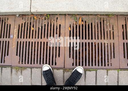 Das Kanalgitter auf dem Bürgersteig ist aus nächster Nähe rostig Stockfoto