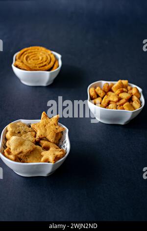 Verschiedene, frische Diwali-Snacks oder farale Dinge gefüllt in weißen Schüsseln mit einem klaren schwarzen Hintergrund. Stockfoto