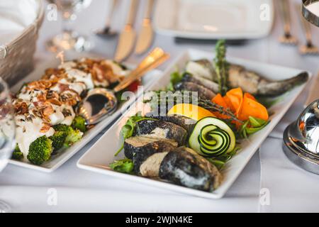 Rechteckige weiße Porzellanplatten mit kalten Fisch-Snacks, Gemüse stehen auf dem Tischrestaurant. Stockfoto