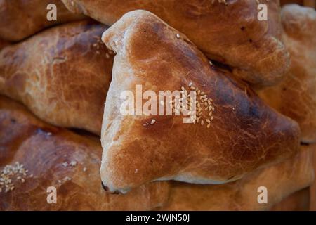 Nationale asiatische Küche. Samsa, Samosa, im Ofen gebackener dreieckiger Kuchen mit Sesamsamen, mit Rindfleisch oder Hühnerfleisch, aus der Nähe. Traditionelles Foo Stockfoto